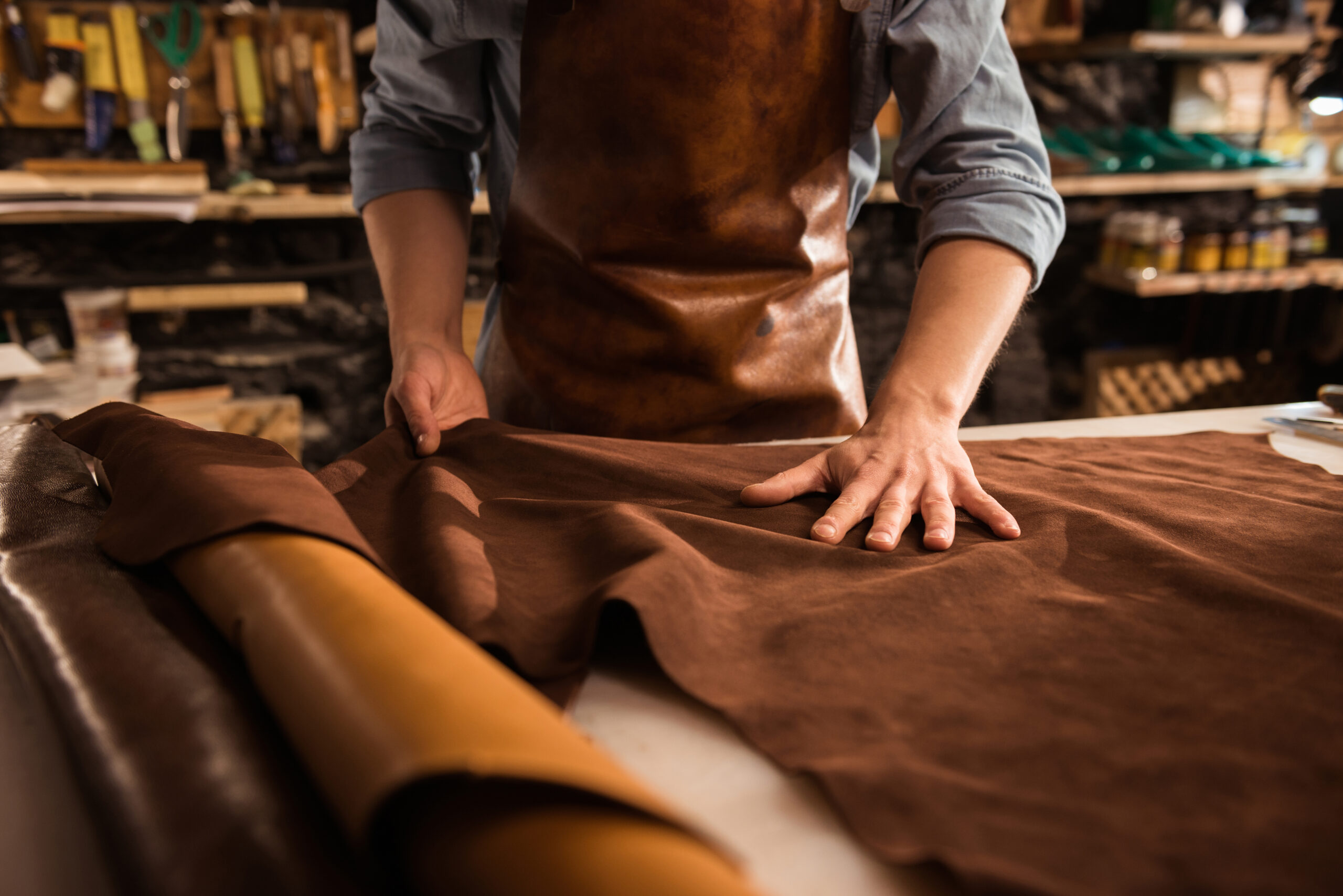 Close up of a cobbler working with leather textile at his workshop